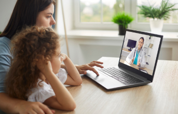 Mother and daughter meeting video call with doctor on laptop